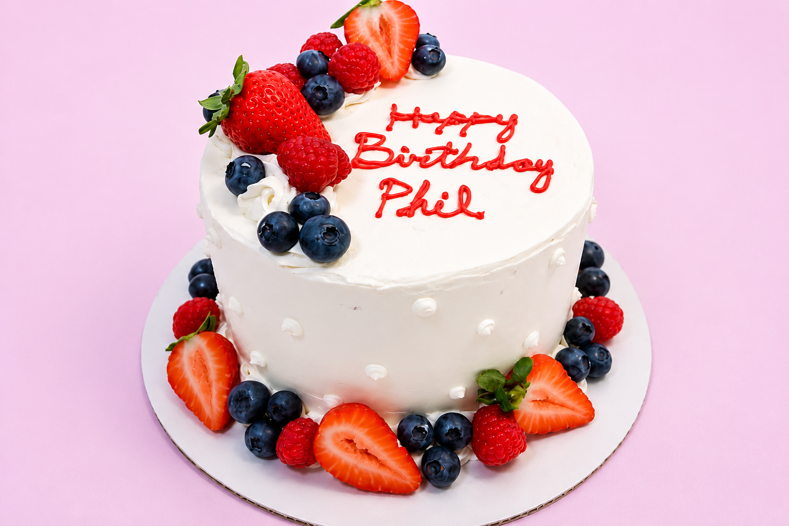 White buttercream cake topped with fresh strawberries, blueberries, and raspberries